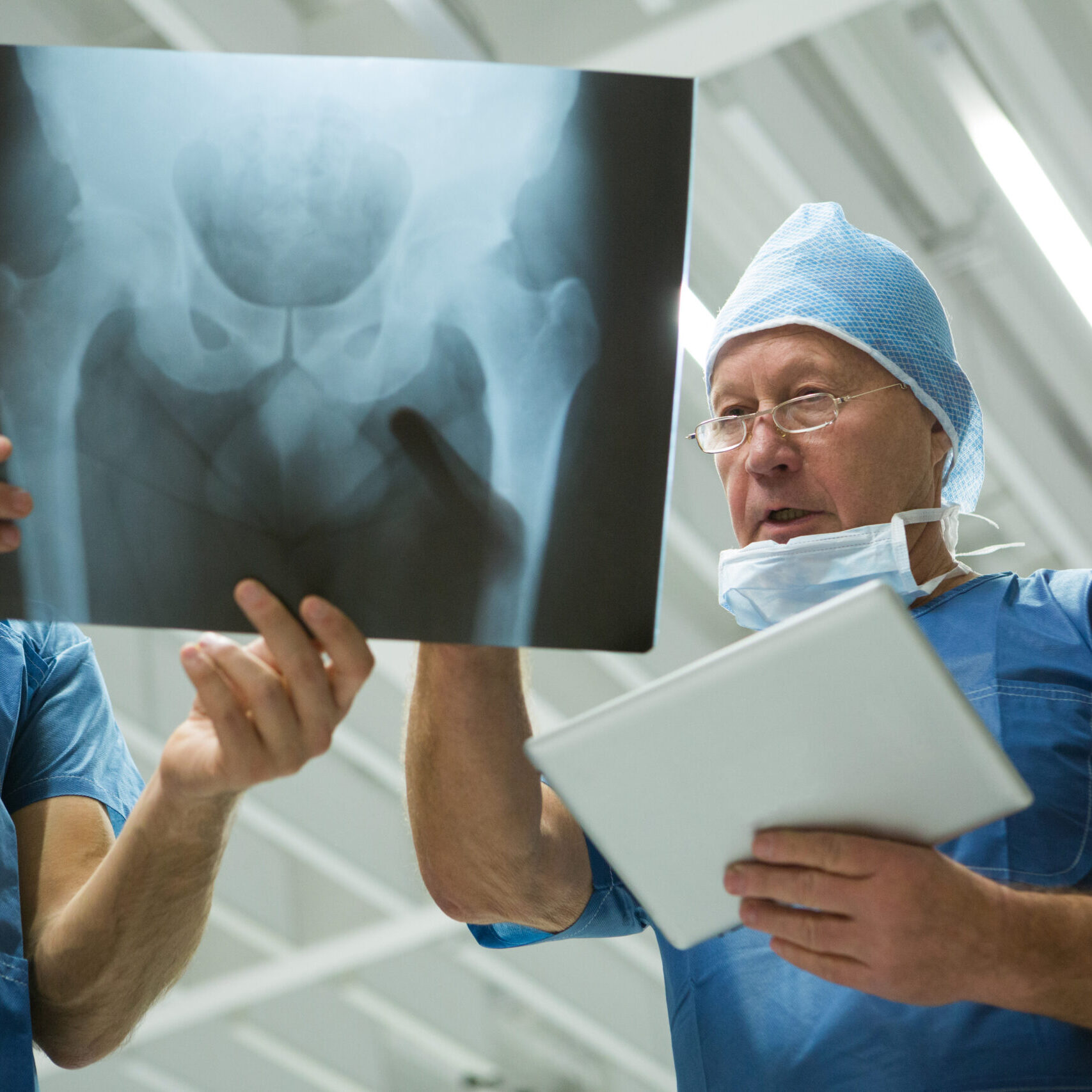 Male surgeons holding digital tablet while discussing x-ray in hospital